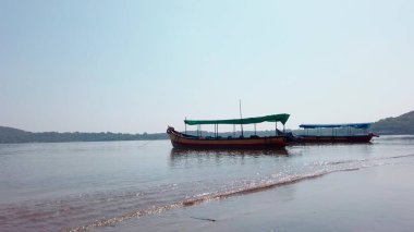 Güneşli bir günde bulutsuz mavi gökyüzüne karşı durgun deniz suyunda yüzen insanla parlak bir turist teknesi.