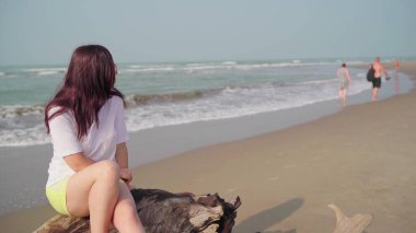 Kadın turist dalgalı denizin yakınındaki kumsalda dinleniyor..