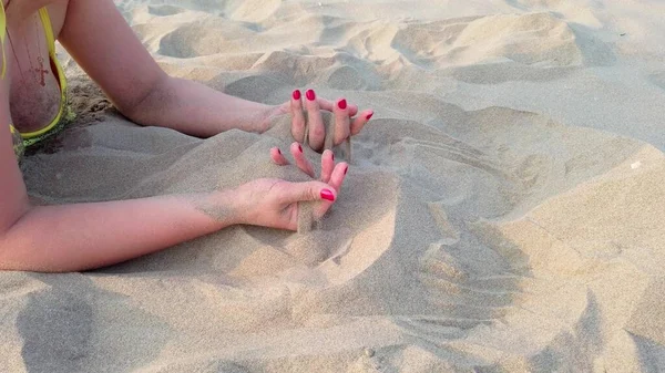 女人的手在她的手掌上沾沙子沙子从她手中滑落在沙滩上 — 图库照片