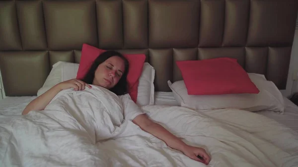 美しい若い女性が大きなベッドで目を覚ます — ストック写真