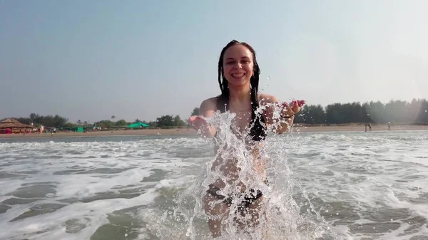 美丽快乐的女人在海里泼水 穿黑色比基尼的女孩在水里玩得很开心 — 图库照片