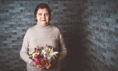 Bayram kutlamaları sırasında elinde bir buket renkli çiçek taşıyan tanınmamış yaşlı bayan.
