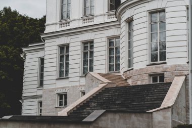 Lüks malikanenin dışından merdiveni ve güneşli yaz gününde birçok penceresi olan.