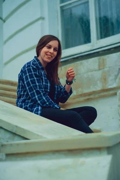 Молодая красивая женщина позирует на лестнице поместья. Взрослая улыбающаяся женщина сидит на ступенях Дворца. — стоковое фото