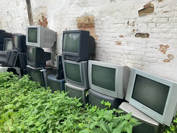Bogoroditsk, Rusia 16 Juli 2020: Banyak TV tua di jalan dekat dinding rumah. Kelompok melemparkan keluar televisi kuno. — Stok Foto