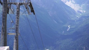 Bulutlu havada, dağın tepesinde bir kablo var. Dağlık arazide bankları olan modern bir halat..