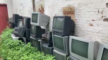 Evin duvarının yanında bir sürü eski televizyon var. Atılmış kadim televizyonlar grubu.