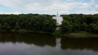 Nehir kıyısındaki konak ve ağaçlar. Bulutlu bir günde nehir kıyısındaki lüks ev ve yeşil ağaçlar
