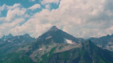 Dağ zirveleri bulutlu gökyüzüne karşı. Güneşli bir günde parlak bulutlu gökyüzüne uzanan muhteşem kayaların zirveleri.