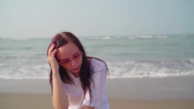 Kumsalda rahat bir kadın oturuyor.