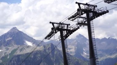 Bulutlu havada, dağın tepesinde bir kablo var. Dağlık arazide bankları olan modern bir halat..