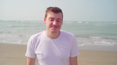 Denizin önündeki genç adam başını sallıyor.