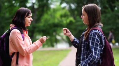 Genç kadınlar yaz parkında taş kağıt makas oynuyorlar. Oyuncu kadınlar elle oyun oynuyorlar.