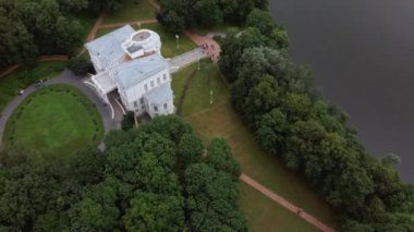 Nehir kıyısındaki konak ve ağaçlar. Bulutlu bir günde nehir kıyısındaki lüks ev ve yeşil ağaçlar