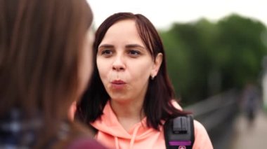 Dersten sonra konuşan mutlu öğrenciler. Sırt çantalı neşeli genç bir kadın. Üniversite eğitiminden sonra köprüde dururken gülümsüyor ve kız arkadaşıyla konuşuyor.