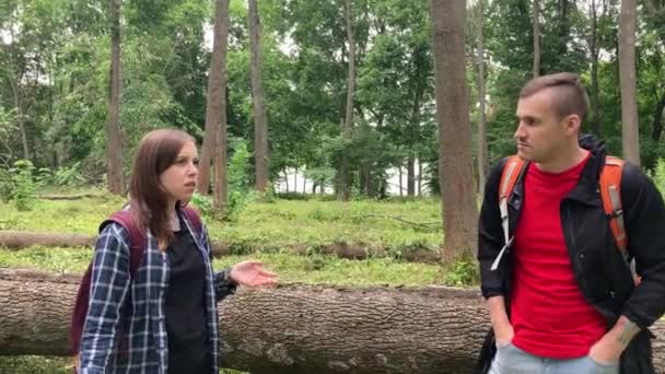 Mujer joven y hombre hablando en el bosque. Amigos reunidos en el parque forestal y conversando. — Vídeo de stock