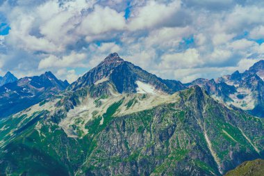 Güneşli bir günde parlak bulutlu gökyüzüne uzanan muhteşem kayaların zirveleri.