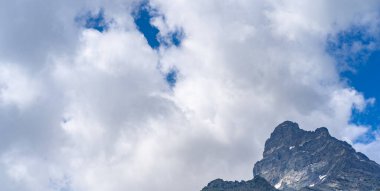 Yaz mevsiminde güzel bir dağ manzarası. Bulutlu havada karlı, kudretli dağlar.