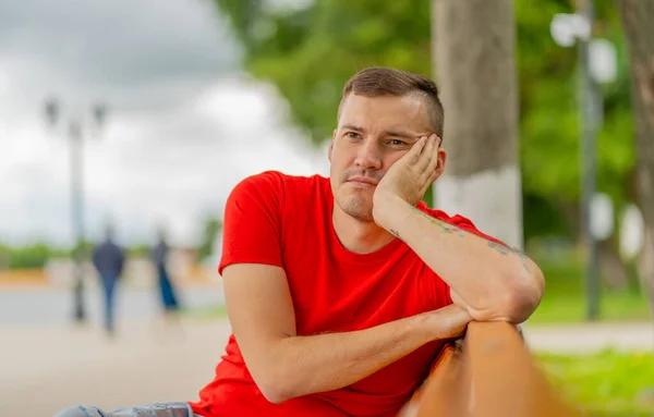 Erwachsener Mann Rotem Shirt Und Jeans Sitzt Auf Bank Und — Stockfoto