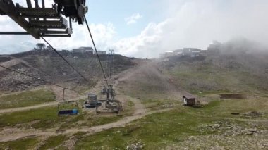 Bulutlu havada, dağın tepesinde bir kablo var. Dağlık arazide bankları olan modern bir halat..
