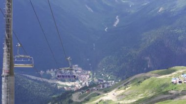 Bulutlu havada, dağın tepesinde bir kablo var. Dağlık arazide bankları olan modern bir halat..