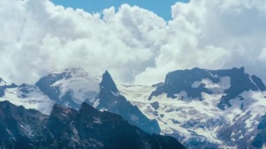 Resimli bir manzara var. Dağ bulutlu gökyüzüne karşı. Mavi gökyüzünde yüzen bulutlar dağ sırtı üzerinde