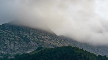 Yüzen bulutları olan güzel dağ manzarası. Bulutlar gökyüzünü sıkılaştırıyor ve dağları sarıyor. Gün batımı geliyor..
