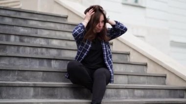 Sarayın merdivenlerinde oturan gülümseyen kadın saçlarına dokunuyor..