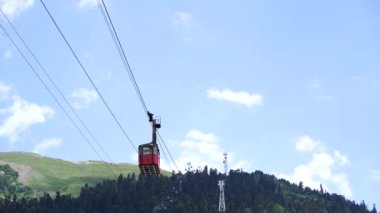 Bulutlu havada, dağın tepesinde bir kablo var. Dağlık arazide bankları olan modern bir halat..