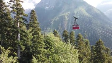 Bulutlu havada, dağın tepesinde bir kablo var. Dağlık arazide bankları olan modern bir halat..