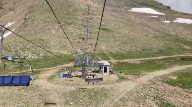 Bulutlu havada, dağın tepesinde bir kablo var. Dağlık arazide bankları olan modern bir halat..
