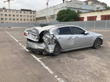 Buruşuk kapüşonlu ve tamponlu bir araba. Asfaltlı park yerine park etmiş buruşuk metal şapkalı eski bir araba..