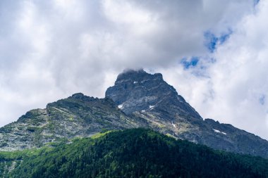 Yaz mevsiminde güzel bir dağ manzarası. Bulutlu havada karlı, kudretli dağlar.