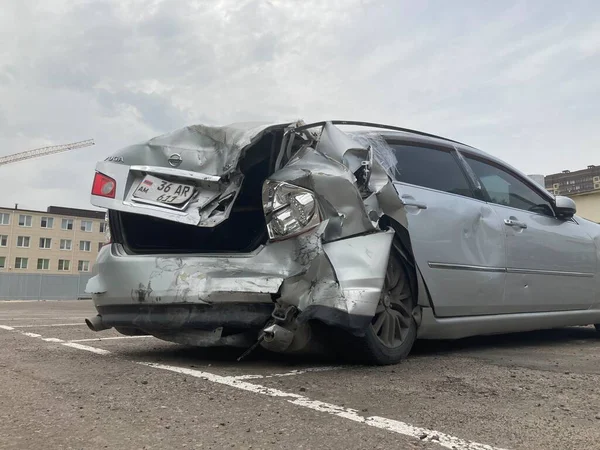 Buruşuk kapüşonlu ve tamponlu bir araba. Asfaltlı park yerine park etmiş buruşuk metal şapkalı eski bir araba..