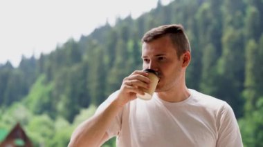 Genç yakışıklı adam, dağ manzaralı kahve içiyor. 