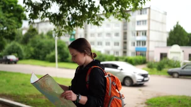 Zblízka cestování mladá žena s batohem a mapou procházky po městě. Ženské turistické čtení a zkoumání mapy, stojící na ulici. — Stock video