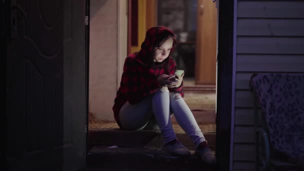 Mujer Joven Sentada Porche Mirando Teléfono Móvil Por Noche Mujer — Vídeo de stock