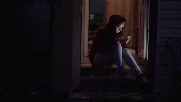 Jeune Femme Assise Sur Porche Parcourant Téléphone Mobile Nuit Chat — Video