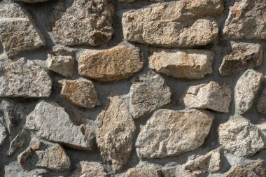 Dikişleri olan eski taşların dokusu. Sefil duvarcılığa yakın çekim. Değişik antik kaldırım taşlarından yapılmış taş duvar.