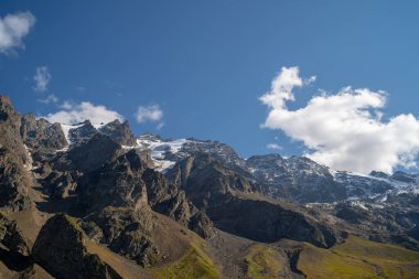 Resimli bir manzara var. Dağ bulutlu gökyüzüne karşı. Mavi gökyüzünde yüzen bulutlar dağ sırtı üzerinde