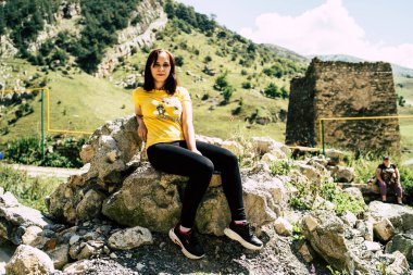 Tepede oturan genç bir kadın. Hayalperest kadın yüksekte oturuyor ve güneşli bir günde güneşli bir gökyüzünde bulunan muhteşem kayalıklara bakıyor..