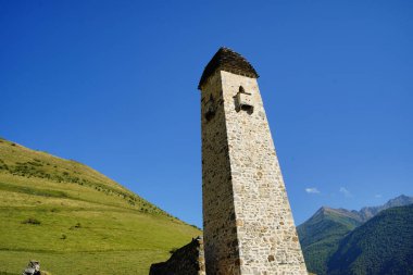 Yeşil dağlık arazideki eski taş kule. Yeşil tepenin üzerinde bulunan antik taş bina yaz günü orman ve sisle kaplı dağlara karşı..