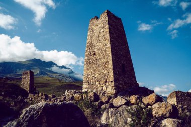 Yeşil dağlık arazideki eski taş kule. Yeşil tepenin üzerinde bulunan antik taş bina yaz günü orman ve sisle kaplı dağlara karşı..