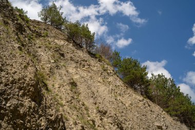 Resimli bir manzara var. Dağ bulutlu gökyüzüne karşı. Mavi gökyüzünde yüzen bulutlar dağ sırtı üzerinde