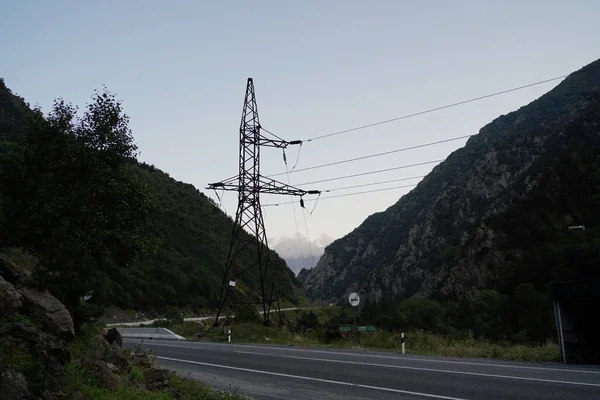 High voltage electric transmission tower in mountainous area. Object of electric power line in mountains in evening