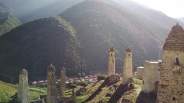 Yeşil dağlık arazide eski taş kuleler. Yeşil tepenin üzerindeki antik taş binalar yaz günü orman ve sisle kaplı dağlara karşı..