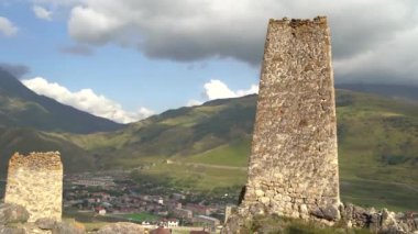 Yeşil dağlık arazide eski taş kuleler. Yeşil tepenin üzerindeki antik taş binalar yaz günü orman ve sisle kaplı dağlara karşı..