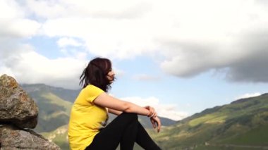 Tepede oturan genç bir kadın. Hayalperest kadın yüksekte oturuyor ve muhteşem kayalıklara bakıyor.