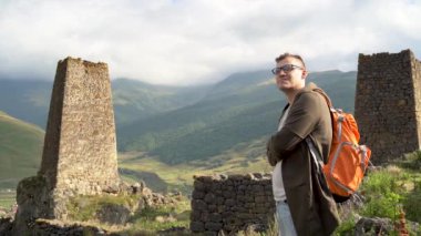 Dağlardaki eski harabelerin yanında duran bir gezgin. Sırt çantalı genç turistin yan görüntüsü