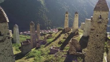 Yeşil dağlık arazide eski taş kuleler. Yeşil tepenin üzerindeki antik taş binalar yaz günü orman ve sisle kaplı dağlara karşı..